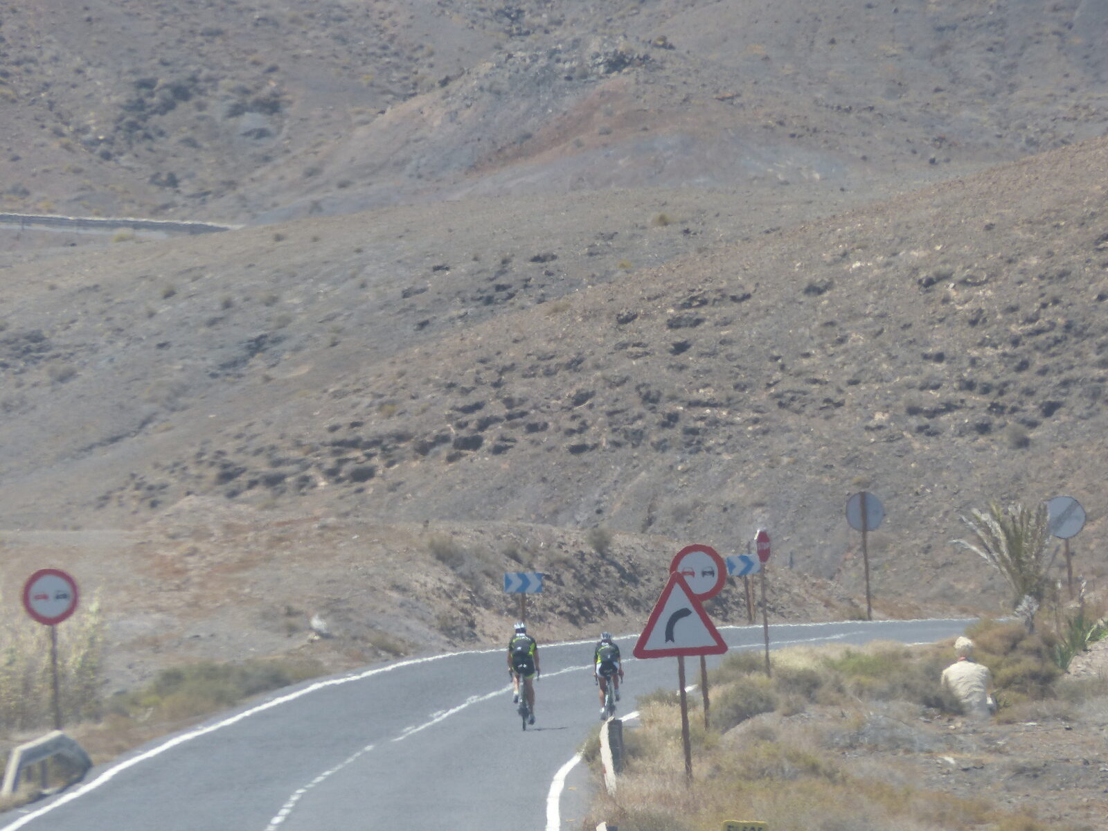 Road cyclists riding past volcanic terrain on the Jandia peninsula in Fuerteventura