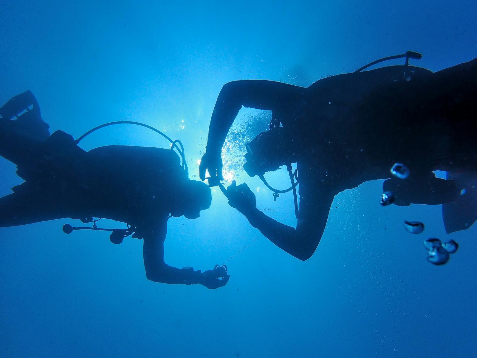 Two scuba divers silhouetted against sunlight in clear Atlantic water off Lanzarote, Canary Islands