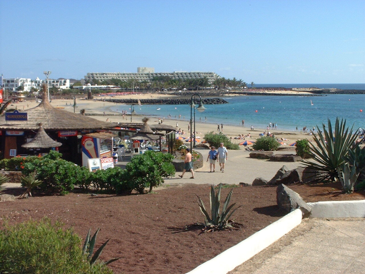 Playa Las Cucharas in Costa Teguise busy with orange and blue beach umbrellas and sunbathers