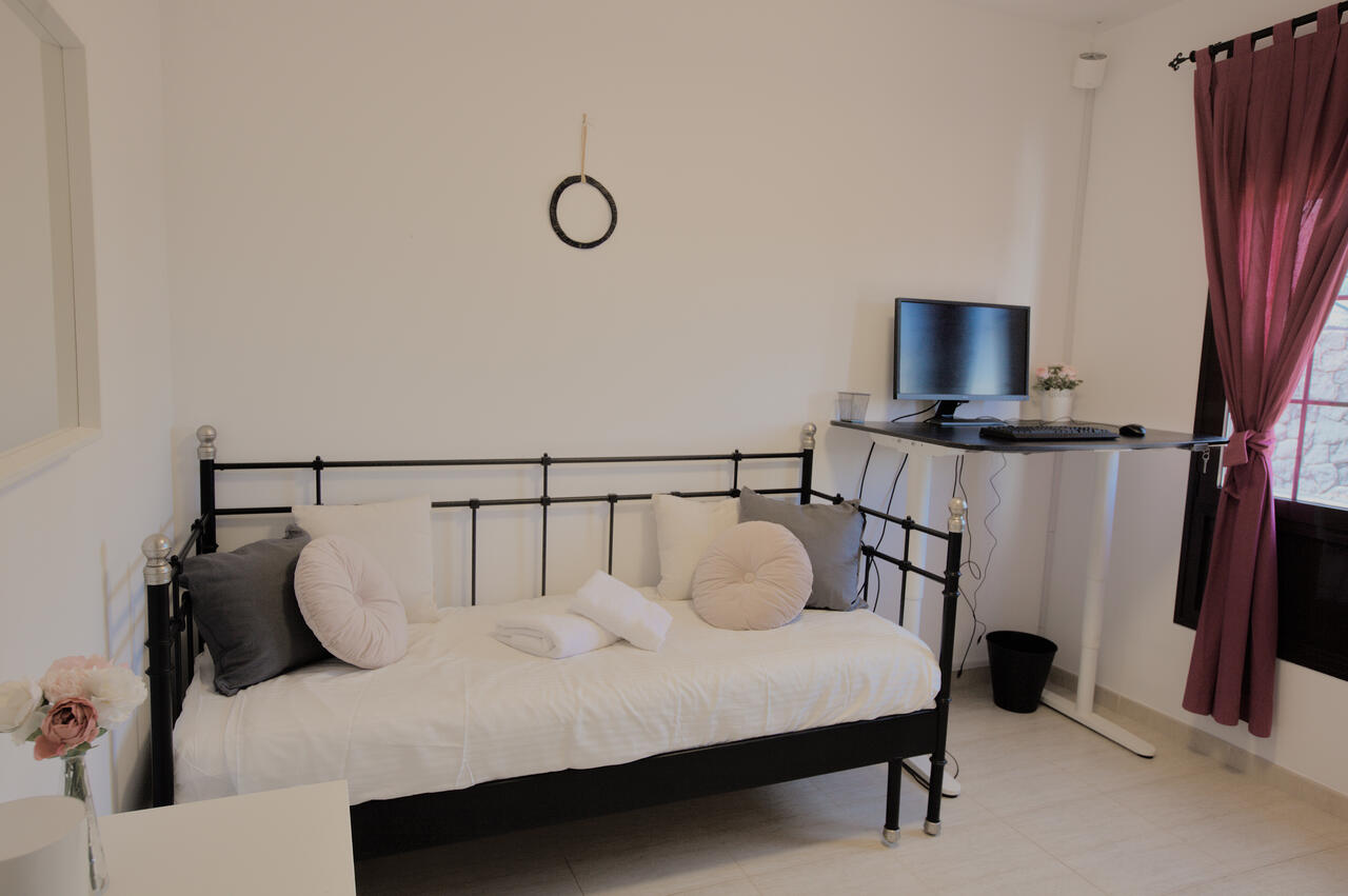 Studio bedroom at Casa Los Alisios in Costa Teguise set up as a workation desk with motorised sit-stand desk, ergonomic chair and natural light. Lanzarote, Canary Islands.