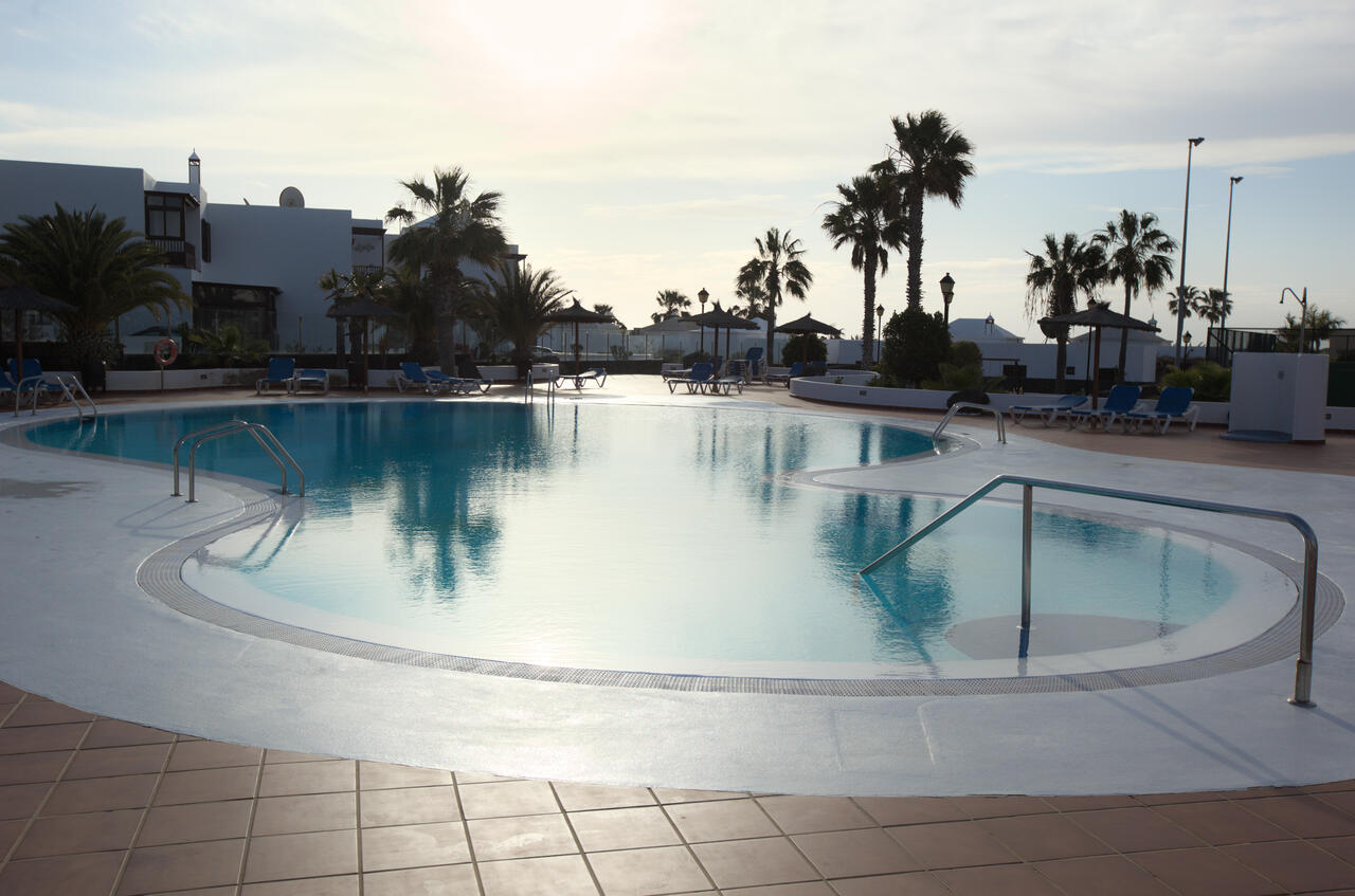 Communal pool with palm trees at the Casa Los Alisios resort complex at sunset, Costa Teguise, Lanzarote